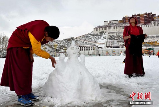 图为僧人在布达拉宫广场堆雪人。