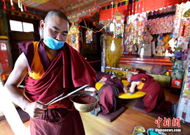 2月22日，僧人正在灌装制作坛城用的彩色细沙。李林 摄