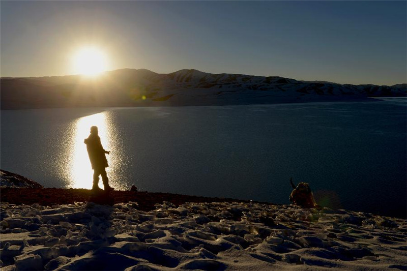 一名摄影爱好者在“鬼湖”拉昂措岸边拍摄落日风光（10月22日摄）。