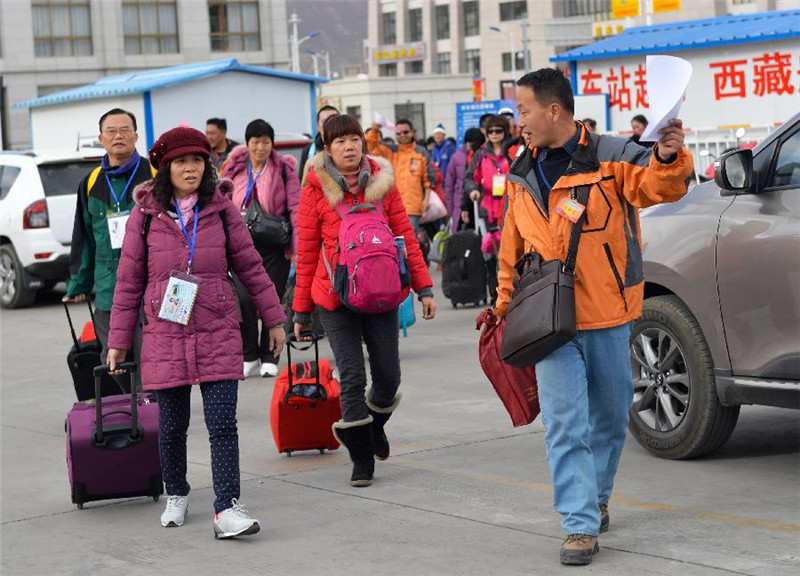 3月21日，游客在工作人员引领下行走在拉萨火车站广场。