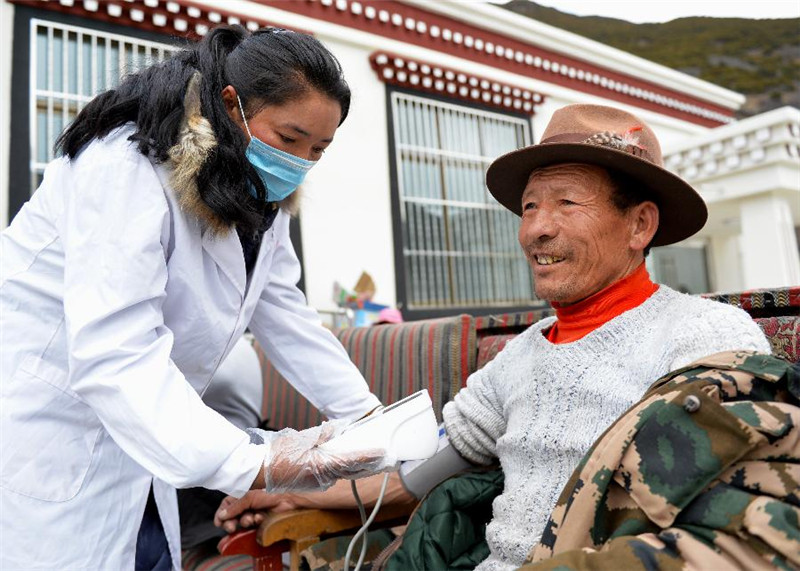 供养中心护士普布卓玛（左）在为五保老人扎西顿珠量血压（3月24日摄）。