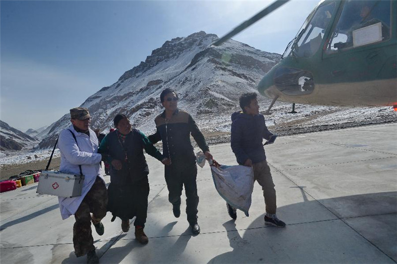 4月21日，西藏札达县楚鲁乡患病村民良久卓玛（左二）在曼札边防连军医罗立军（左一）等人的搀扶下准备搭乘直升机。