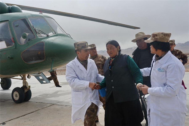 4月21日，西藏札达县楚鲁乡患病村民良久卓玛（中）在阿里军分区医护人员搀扶下走下直升机，被送往阿里地区人民医院进行救治。