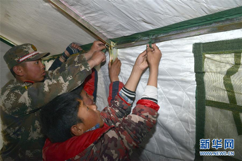 4月26日，武警西藏总队聂拉木县中队战士和当地学生在聂拉木中学操场上搭建救灾帐篷。