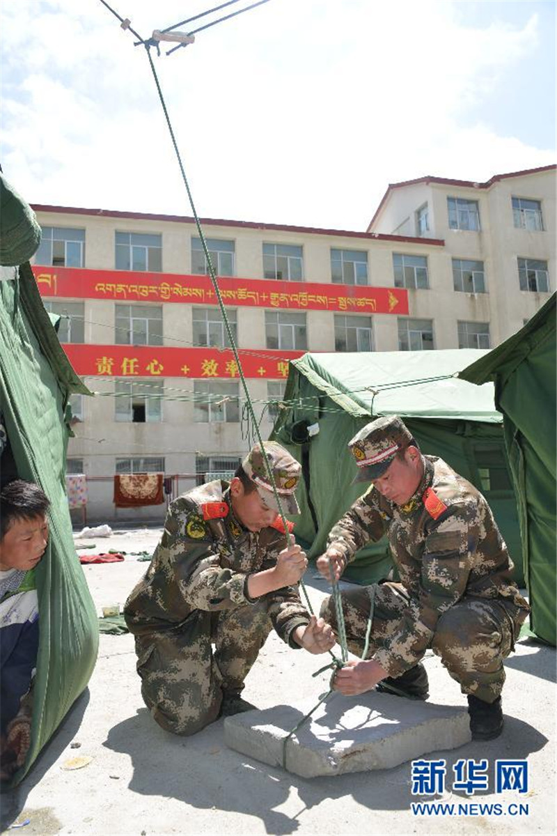 4月26日，武警西藏总队聂拉木县中队战士和当地学生在聂拉木中学操场上搭建救灾帐篷。