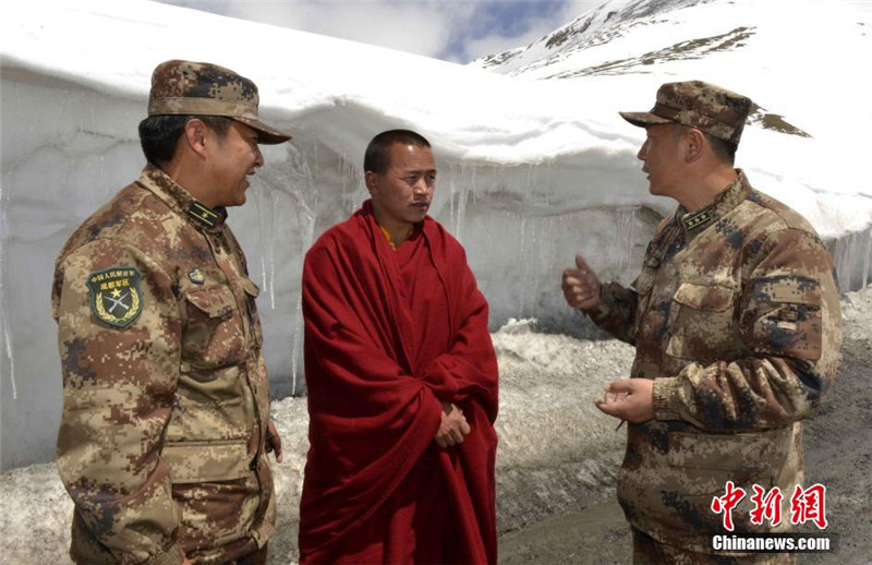4月26日，西藏军区日喀则军分区副司令员顾炳战（图右）向僧人询问吉隆受灾情况。