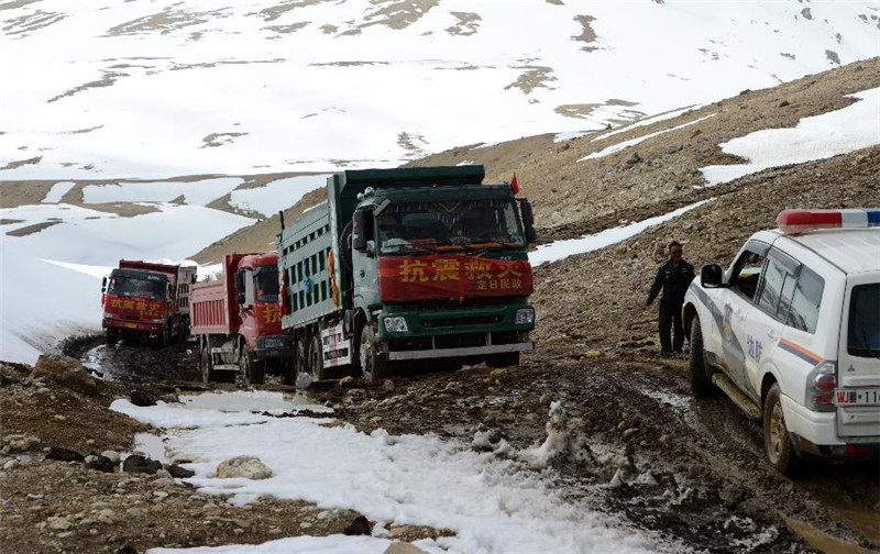 一位交警站在寒风中指挥经过普孜拉山口狭窄路段的救援车辆（4月28日摄）。