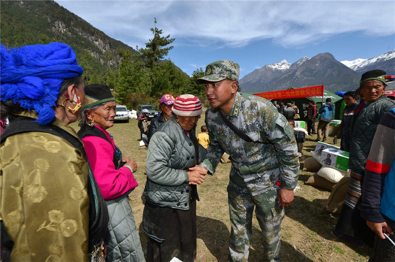图为人武部藏族政工科科长加央利用语言优势向群众了解灾情。（特约记者 张震 摄）
