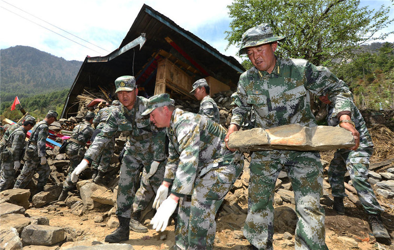 武部专武干部、民兵骨干扎西（右一）与官兵清理废墟。