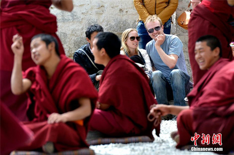 图为5月5日，外国游客在拉萨市色拉寺内观看僧人辩经。