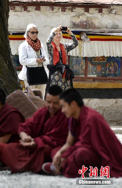 图为5月5日，外国游客在拉萨市色拉寺内拍摄僧人辩经。