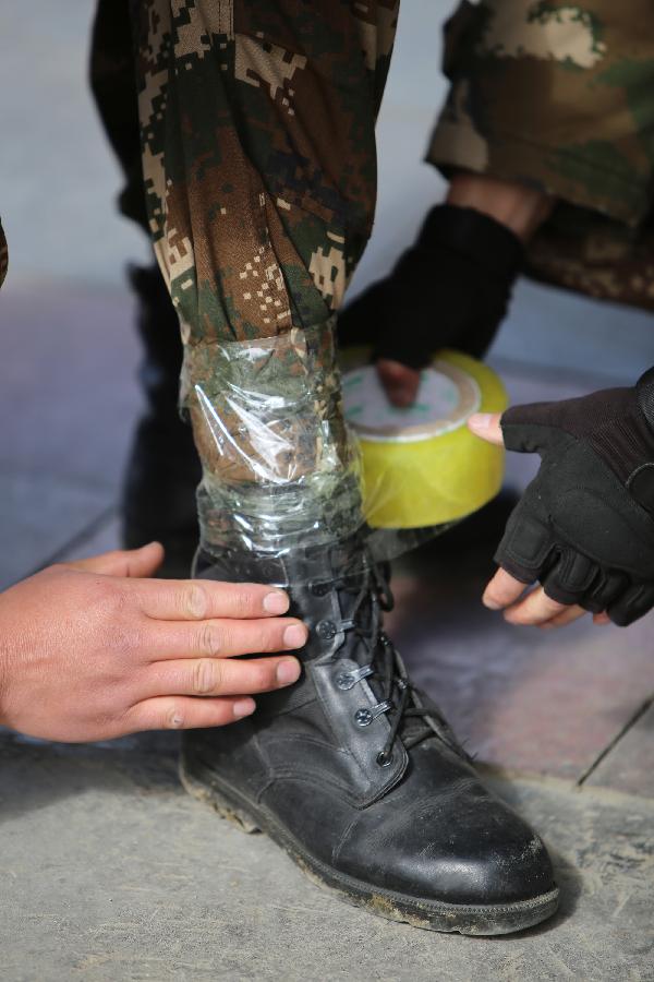 5月8日，西藏公安边防总队阿里边防支队官兵丁嘎柏林边境检查站战士为即将巡逻的战友脚上缠胶带，防止鞋里进雪。