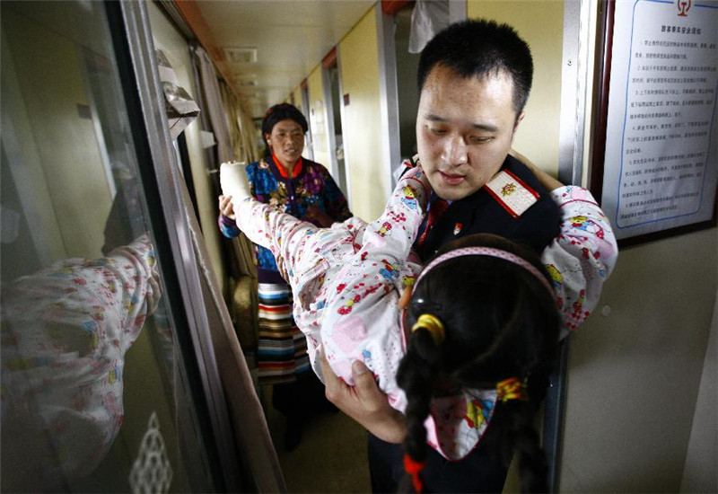 5月12日，Z164次列车到达拉萨站，列车员傅博抱着一名患儿下车。
