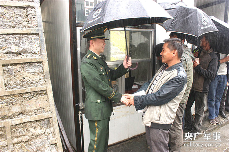 图为边民感谢边检官兵的服务，紧紧握住官兵的手。