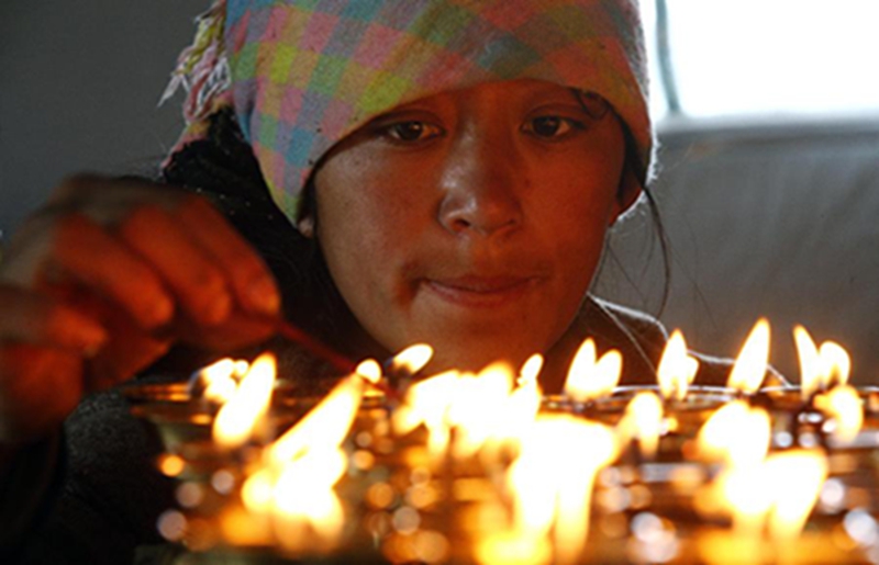  西藏吉隆县吉隆镇乃村的丹增普次为在地震中去世的妹妹次仁德吉点燃酥油灯（5月15日摄）。