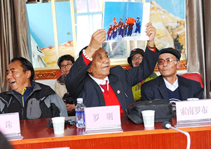 5月27日，罗则（前中）举起1975年中国登山队登上珠峰展示国旗的照片。