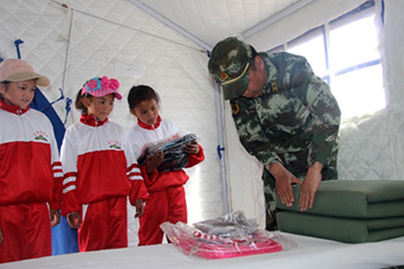 西藏公安边防总队吉隆边防检查站的警官在为灾区儿童示范叠被子（5月31日摄）。