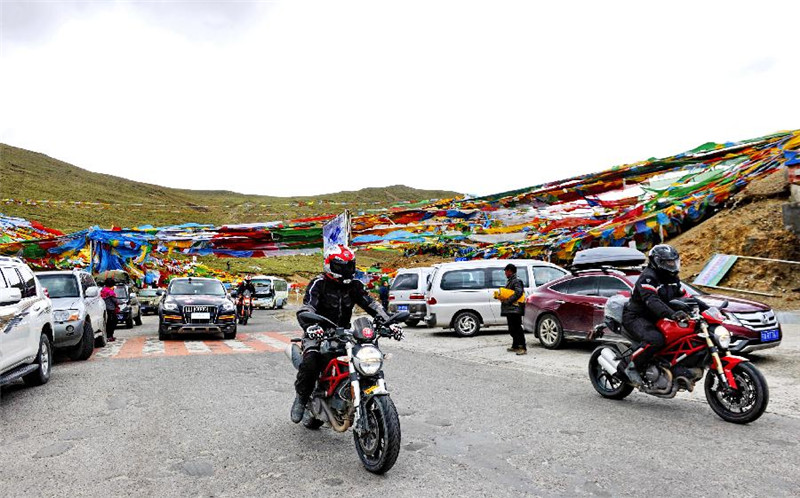 车辆穿越挂满五彩经幡的西藏米拉山口（6月14日摄）。