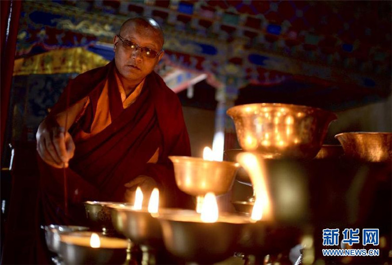 6月23日，僧人旦增群培在东嘎寺内点酥油灯。