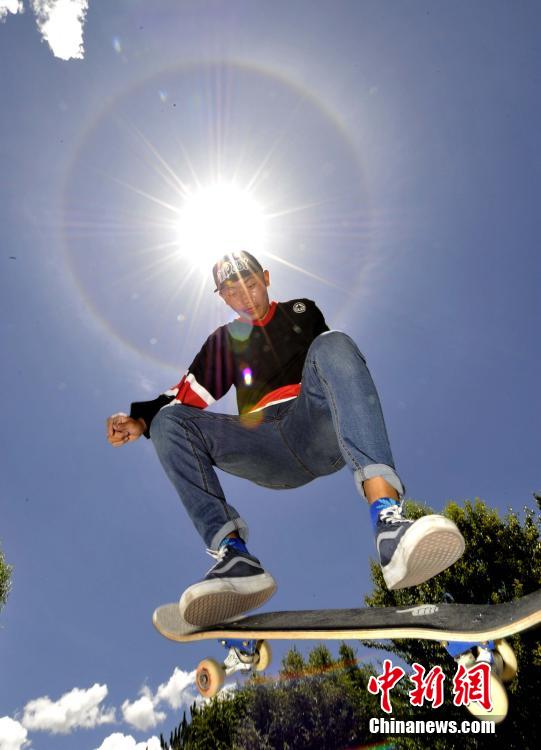 7月21日，正在玩滑板的格桑朗杰恰好穿越日晕奇观。