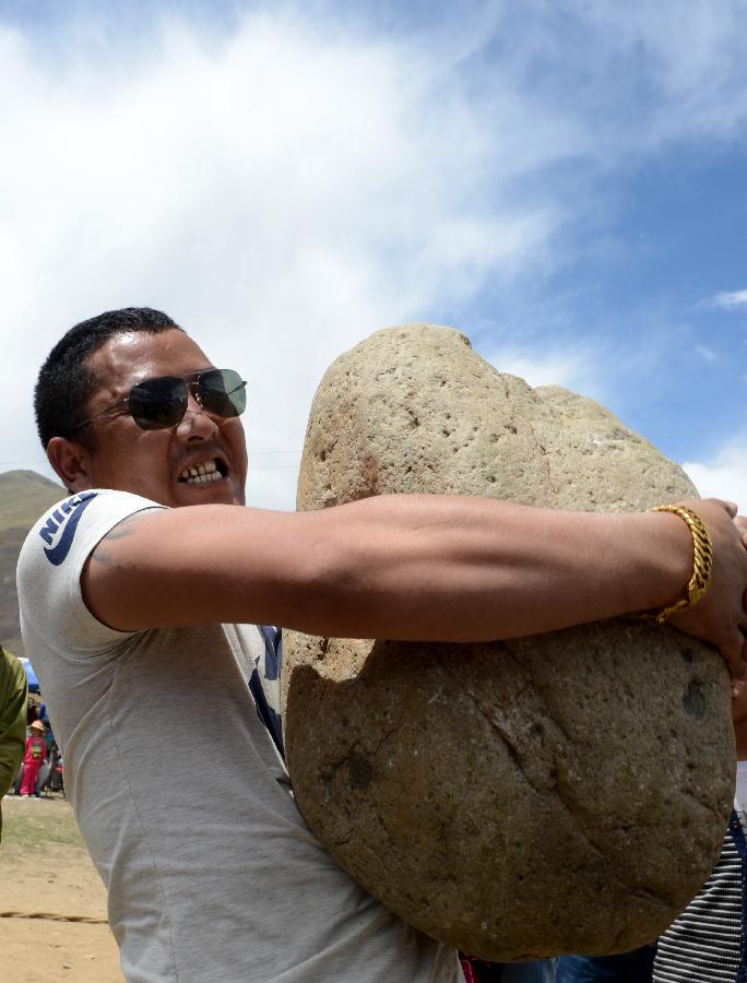 7月26日，一个村民在藏族传统体育活动抱石头比赛中扛起上百斤的大石头。