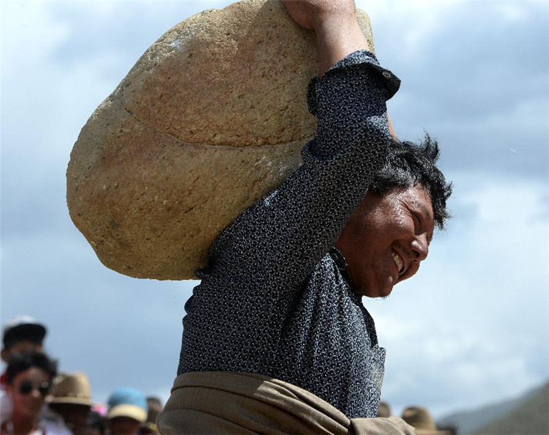 7月26日，一个村民在藏族传统体育活动抱石头比赛中扛起上百斤的大石头。