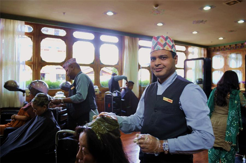 尼泊尔理发师纳根达（前）长得很像印度影视明星沙鲁克·汗，很多顾客都愿意找他为自己理发（7月30日摄）。