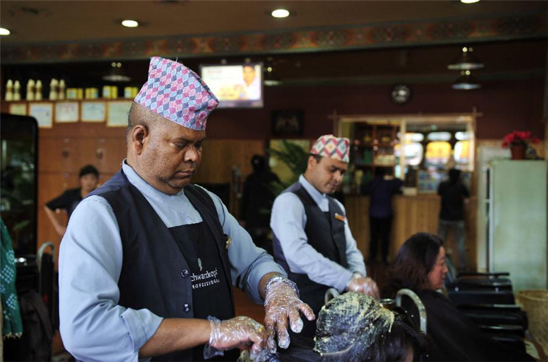 原尼泊尔理发师杰拉（左）为顾客使用一种叫“故蒂”的植物染料染发。这种染发原料由于兼顾头皮的保养，深受藏族群众的喜爱（7月30日摄）。