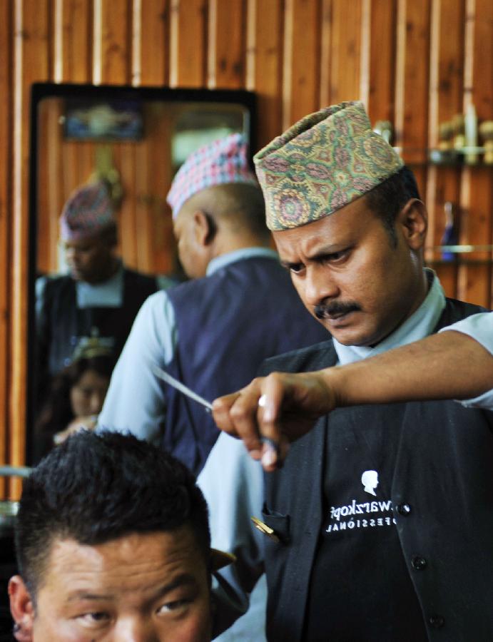 尼泊尔理发师加地秀正在认真为顾客理发（7月30日摄）。
