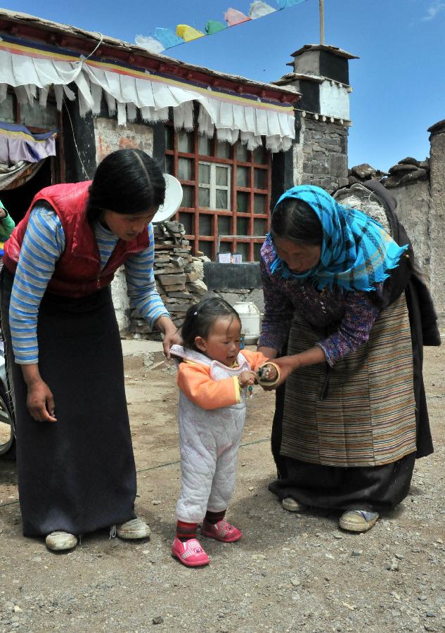 这是术后5年的斯求卓玛（右）帮助女儿照顾学走路的外孙女（2015年7月15日摄）