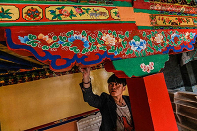 在西藏拉萨八廓街，一名画师在洛桑扎西的“吉日卓康”古宅酒店房梁上绘画（8月5日摄）。