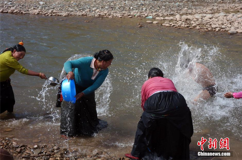 图为当地民众在巴曲河畔沐浴洗头，除去疾病，迎来好运。中新社发 孙睿 摄