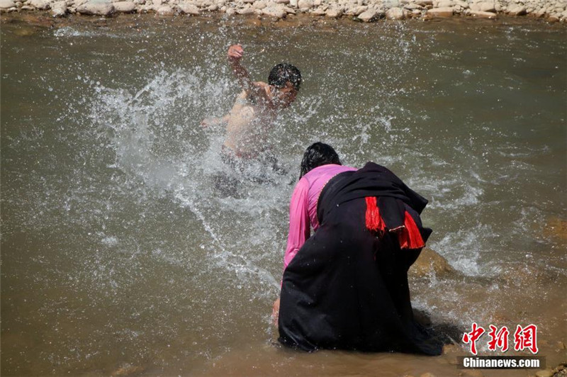 图为当地民众在巴曲河畔沐浴洗头，除去疾病，迎来好运。中新社发 孙睿 摄