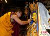 图为班禅为释迦牟尼佛等身金像像面部涂绘金粉。 中新社记者 李林 摄