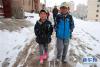 5月26日，小朋友走在甘肃甘南藏族自治州合作市雪后湿滑的道路上。