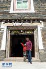 在甲根坝乡木雅村经营民居“秋竹之家”的邓珠扎西（右）和儿子在民居前留影。2016年5月28日，新华社记者金马梦妮摄。