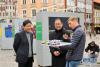 10月7日，在拉脱维亚首都里加老城中心多姆广场，摄影师亚尼斯·莱赞斯（右）向中国驻拉大使黄勇（中）介绍图片展。