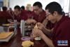 来自青海省黄南藏族自治州同仁县的僧人丹增凯智（右一）在食堂用餐（11月16日摄）。