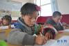 11月24日，在甘肃省天祝县抓喜秀龙乡代乾教学点，6岁的学前班孩子央尖卓玛（前）在自习课上练习藏文写字。