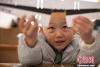 图为3月18日在西藏“气象模型拼装大赛”上格萨平措小朋友展示他拼好的纸模“机翼”。 何蓬磊 摄