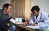 4月11日，青海省海北藏族自治州刚察县泉吉乡切吉村卫生所村医官保才旦（右）在牧民加布家中为他测量血压。