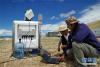 考察队成员李照国（右）与王少影在色林错湖畔架设的激光测风雷达旁进行数据采集工作（7月4日摄）。