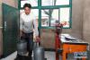 7月20日，在甘南藏族自治州燎原乳业有限责任公司多河村收奶站，一名牧民提着鲜牦牛奶准备过称。 陈晔华 摄