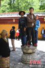 图为西藏民众站在石台上观看藏戏表演。 中新社记者 崔楠 摄