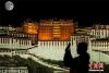 图为游客在布达拉宫广场赏月并拍照留念。（双重曝光） 中新社记者 何蓬磊 摄