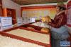 西藏阿里地区改则县物玛乡抢古村村长布次仁在牧业集体经济合作社畜产品展示厅内查看酥油(3月15日摄)。新华社记者 刘东君 摄