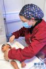 玉树藏族自治州人民医院医生吉安在新生儿/儿童重症监护室为新生儿检查身体（4月12日摄）。