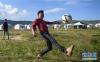 在甘南藏族自治州碌曲县尕海镇尕秀村帐篷城度假区，牧民在草原上踢球（8月10日摄）。新华社记者 陈斌 摄