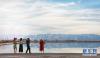 8月18日，游客在察尔汗盐湖边拍照留念。新华社记者 田文杰 摄
