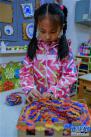 11月30日，一名女孩在教室里用纸盒制作的工具编织爱心围巾。新华社记者 徐昱 摄